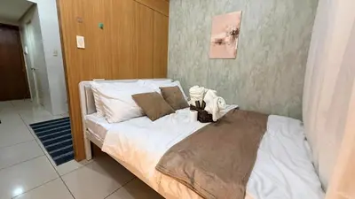 a bedroom with a bed with white sheets and pillows at Classy Pool view low floor Condo near MoA in Manila