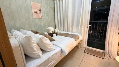 a bed with white pillows in a room with a window at Classy Pool view low floor Condo near MoA in Manila