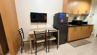 a kitchen with a table with chairs and a refrigerator at Classy Pool view low floor Condo near MoA in Manila