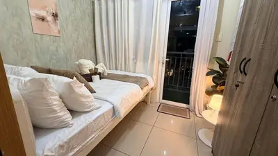 a small room with a bed and a balcony at Classy Pool view low floor Condo near MoA in Manila