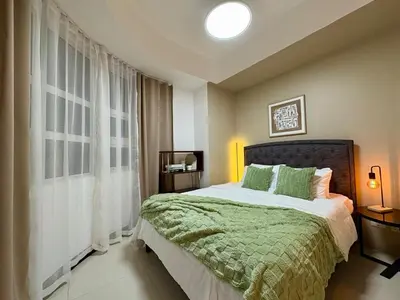 a bedroom with a bed with a green comforter at Stylish 1BR Condo in 101 Newport City Near NAIA in Manila
