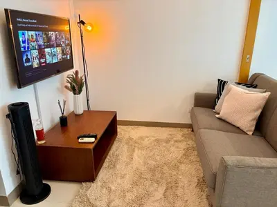 a living room with a couch and a tv at Aesthetic Modern Suite 1BR One Uptown Residence BGC in Manila