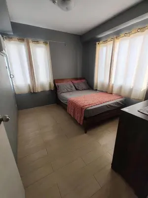 a small bedroom with a bed and two windows at Condotels Villa Topaz in Manila