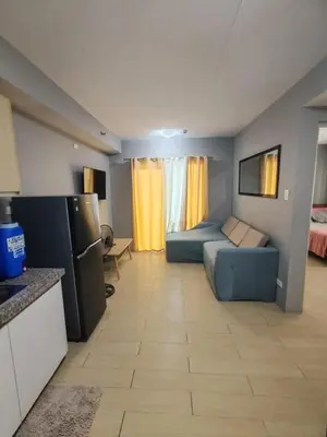 a living room with a blue couch and a kitchen at Condotels Villa Topaz in Manila
