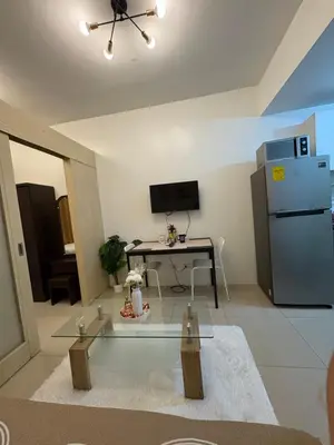 a living room with a glass table and a refrigerator at Jazz Residences in Manila