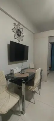 a dining room table with chairs and a flat screen tv at Sea Residences MOA Area in Pasay City in Manila