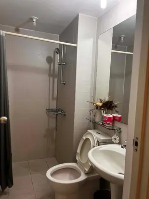 a bathroom with a shower and a toilet and a sink at Zyron Suite in Manila
