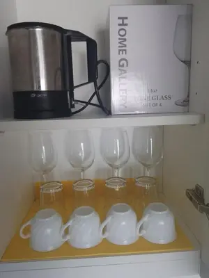 a shelf with wine glasses and a coffee maker at Zyron Suite in Manila