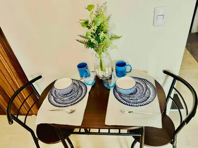 a wooden table with two plates and a vase with flowers at Cozy BB in the Heart of Quezon City in Manila