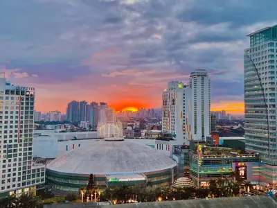 a view of a city at sunset with a building at Cozy BB in the Heart of Quezon City in Manila