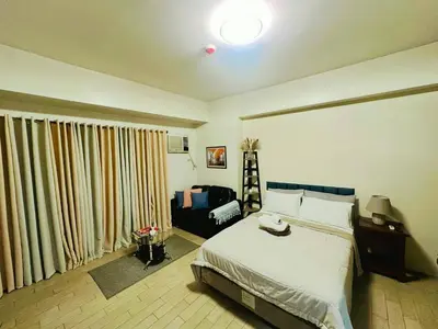 a bedroom with a bed and a large window at Cozy BB in the Heart of Quezon City in Manila
