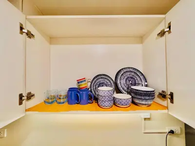 a cupboard with plates and cups on a shelf at Cozy BB in the Heart of Quezon City in Manila