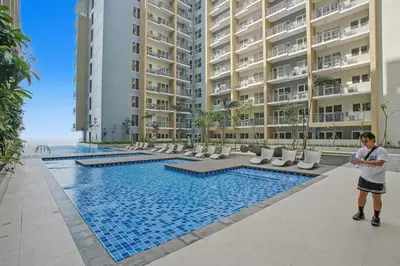 a man standing next to a swimming pool in front of a building at Elegant and Spacious 3BR Home near Okada, Solaire in Manila