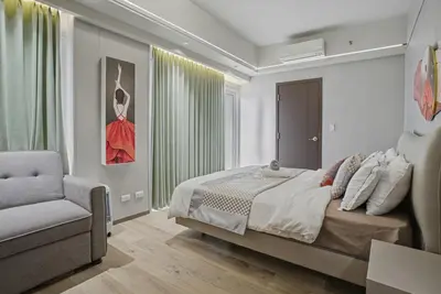 a bedroom with a bed and a chair and a window at Elegant and Spacious 3BR Home near Okada, Solaire in Manila