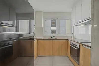 a large kitchen with wooden cabinets and stainless steel appliances at Modern and Spacious 3BR Home near Solaire & Okada in Manila