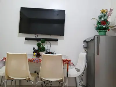 a dining room table with chairs and a television on a wall at Rosaland staycation in Manila