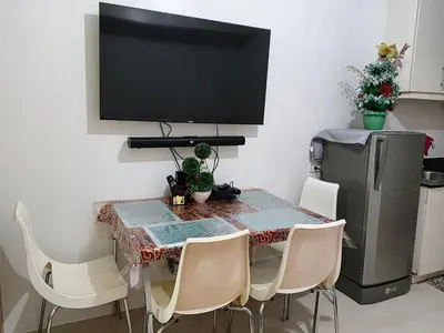 a table with chairs and a television on a wall at Rosaland staycation in Manila