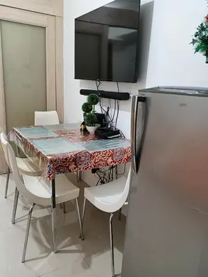 a dining room table with chairs and a television at Rosaland staycation in Manila