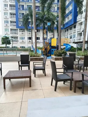 a patio with tables and chairs and a playground at Rosaland staycation in Manila
