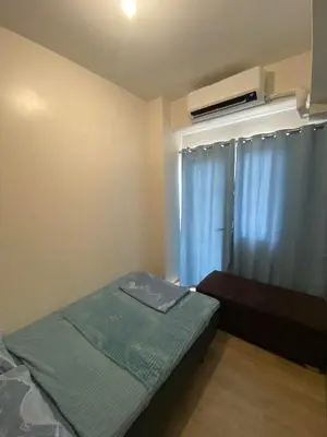 a bedroom with a bed and a window with a air conditioner at Metro Home Staycation in Manila