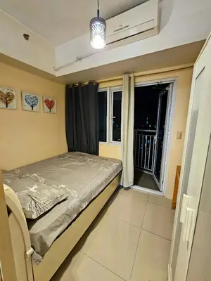 a small bedroom with a bed and a window at Nest & Rest by RanDecz in Manila