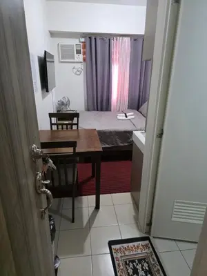 a small room with a bed and a table and a desk at Nicecondotel in Manila