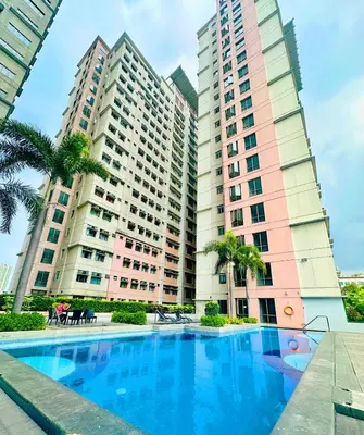 a swimming pool in front of two tall buildings at Cozy Modern Condo in Little Baguio Terraces San Juan City in Manila