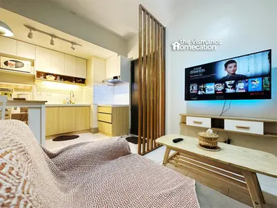 a living room with a couch and a tv and a kitchen at Cozy Modern Condo in Little Baguio Terraces San Juan City in Manila