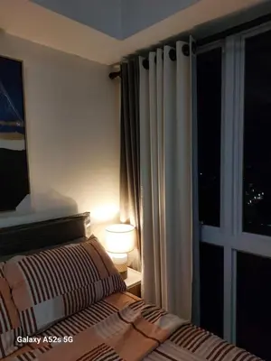 a bedroom with a bed and a window at night at Kasara Urban Resort premium studio staycation by Rain in Manila