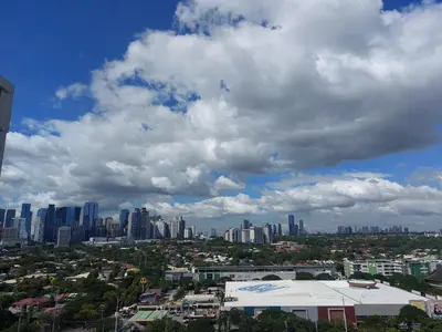 a city skyline under a cloudy sky with buildings at Kasara Urban Resort premium studio staycation by Rain in Manila