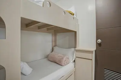 a white bunk bed with a pink pillow in it at Lovely & Spacious 2BR Home near Solaire & Okada in Manila