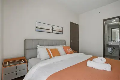 a bedroom with a large bed with orange pillows at Lovely & Spacious 2BR Home near Solaire & Okada in Manila