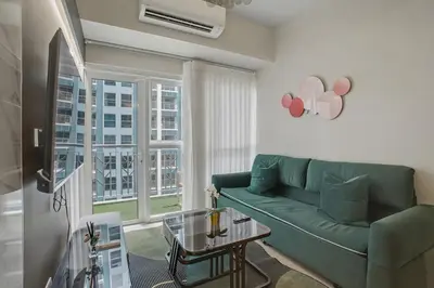 a living room with a green couch and a table at Lovely & Spacious 2BR Home near Solaire & Okada in Manila