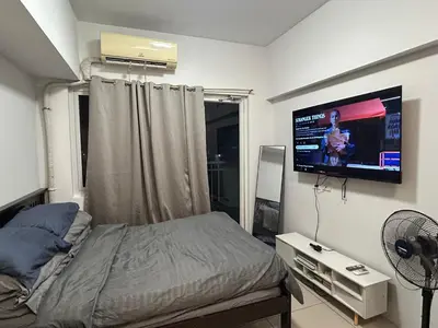 a bedroom with a bed and a flat screen tv at CG Staycation Hub in Manila