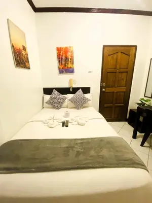 a bedroom with a large white bed with a wooden door at Makati Avenue Suites in Manila