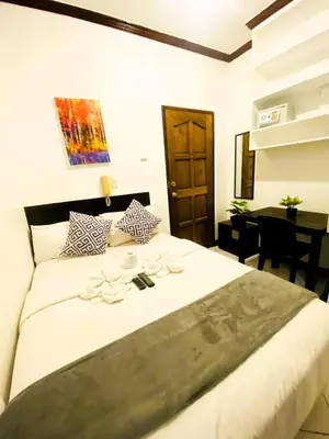 a bedroom with a large white bed with a desk at Makati Avenue Suites in Manila