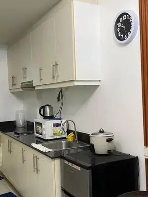 a kitchen with a microwave and a clock on the wall at Stern Staycation Moa in Manila