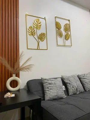 a living room with a gray couch and two pictures on the wall at Stern Staycation Moa in Manila