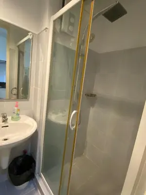a shower with a glass door next to a sink at Stern Staycation Moa in Manila