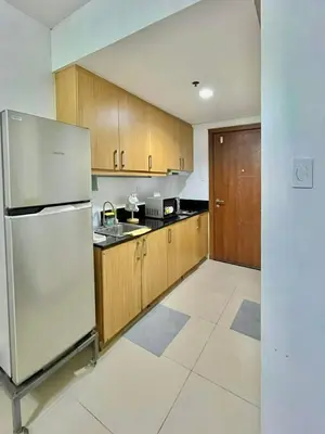 a kitchen with wooden cabinets and a stainless steel refrigerator at MD staycation in Manila