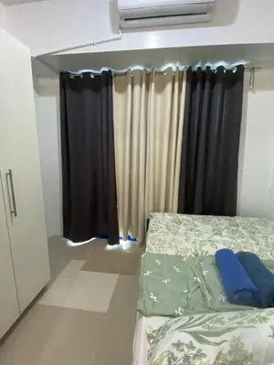 a bedroom with a bed and a window with curtains at Sea Residences Staycation Moa ,Stern Homes in Manila