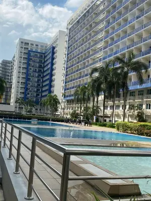 a swimming pool in front of a large building at Sea Residences Staycation Moa ,Stern Homes in Manila