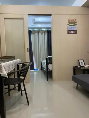 a living room with a table and chairs and a bedroom at Sea Residences Staycation Moa ,Stern Homes in Manila