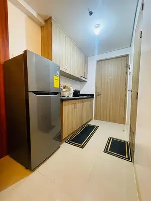 a kitchen with a stainless steel refrigerator and wooden cabinets at H&M staycation SHORE 2 in Manila