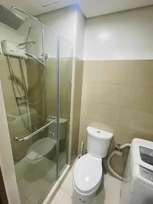 a bathroom with a toilet and a glass shower at H&M staycation SHORE 2 in Manila
