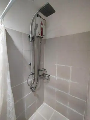 a shower with a shower head in a bathroom at Lornas Staycation in Manila
