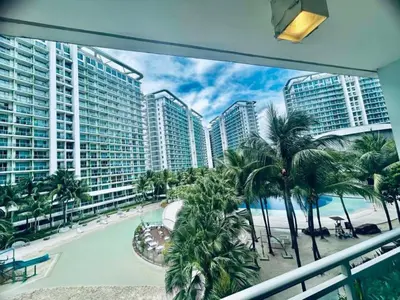 a balcony with a view of a pool and palm trees at Cozy Condos at Azure Urban Resort in Manila