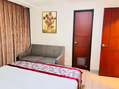 a bedroom with a bed and a chair and a door at Easyworld One Uptown Residence BGC in Manila