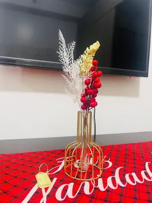 a vase with red berries and flowers on a table at Shore2 Moa ph stay in Manila