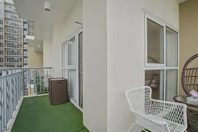 a room with a balcony with a chair and windows at Luxury Home near Solaire and Okada Manila in Manila